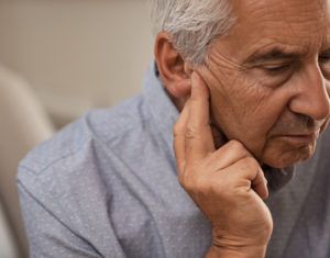 Elderly man attempting to listen by holding hands to his ears