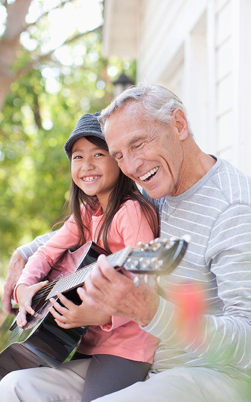 Grandfather and granddaughter playing guitar together