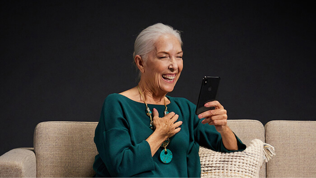 Woman using her phone on couch and laughing