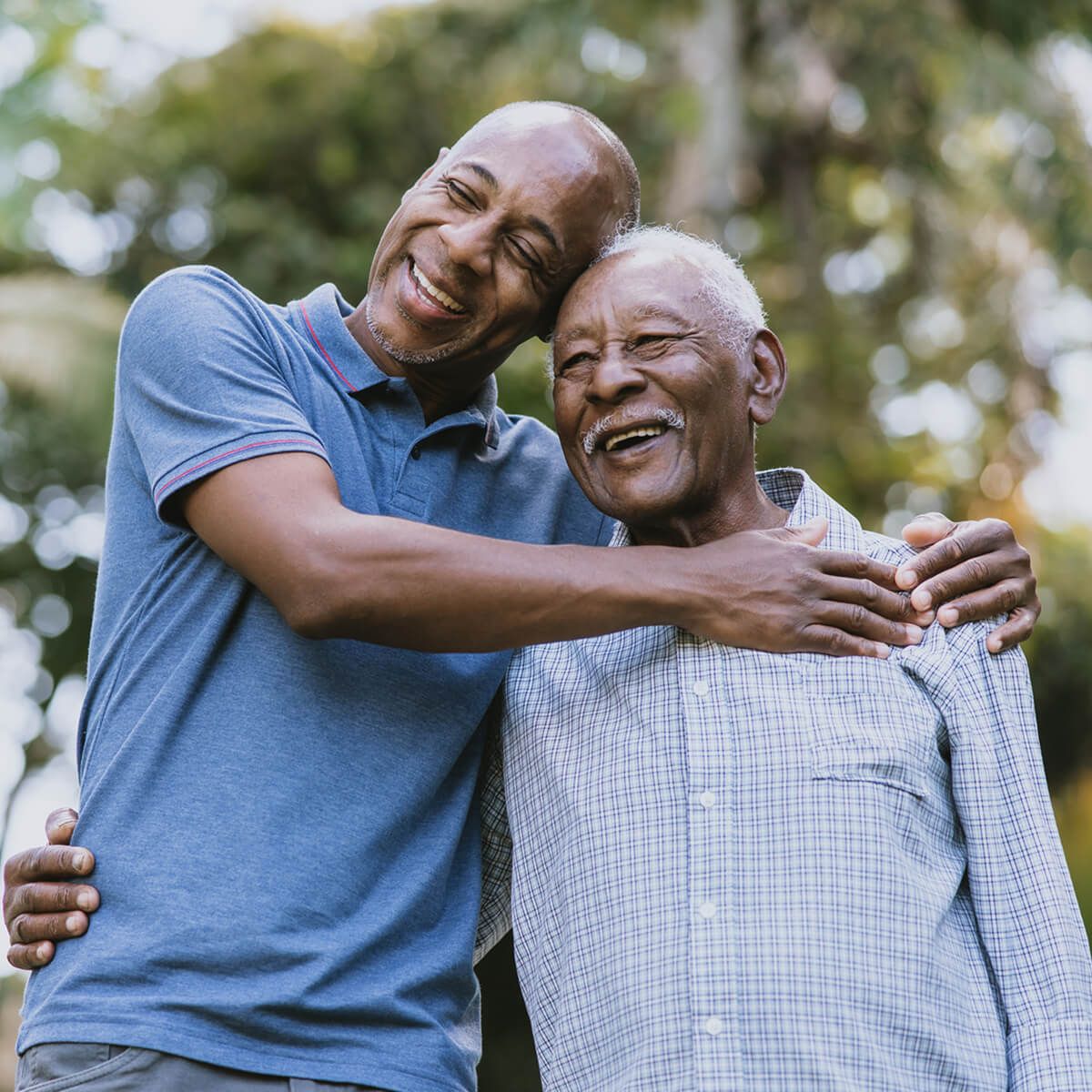 Smiling father and son embracing each other in a sunny outdoor setting